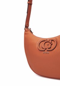 Borsa a spalla in pelle marrone con forma curva, dotata di logo in rilievo e accessori in tono oro. Cinghia regolabile e chiusura con zip.