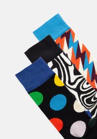 Drei Paar bunte Socken: ein Paar mit blauem Bündchen und Zickzackmuster, ein Paar mit Zebra-Streifen und ein schwarzes Paar mit multicolore-Polka-Dots.