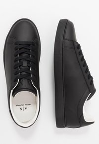 Svarta lädersneakers med en slät yta, rund tå, platta snörningar och en vit inre krage. Gummisula med en enkel design.