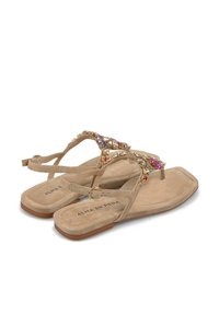 Sandali piatti beige con texture scamosciata, con una fascia decorativa impreziosita da gioielli colorati e un logo discreto sulla soletta.