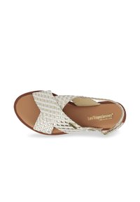 Woven silver leather sandals with crisscross design, padded insole, and brown rubber outsole. Minimalist style with no additional accents.