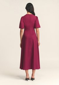 Vino midi-mekko puff-hihalla, sileä rakenne, takana vetoketjusulku ja liehuva helma. Yksinkertainen muotoilu puhtaalla siluetilla.