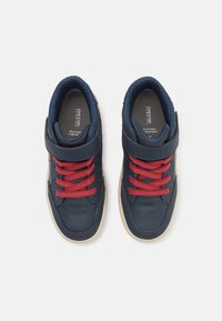 Baskets en cuir bleu marine avec lacets rouges et sangle Velcro. Col rembourré, semelle en caoutchouc et détails perforés pour une meilleure respirabilité.