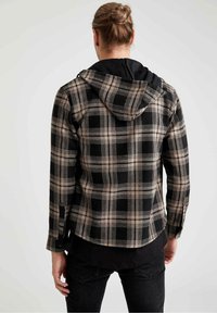 Sort og beige ternet flanneljakke med hætte, med en kontrasterende sort indvendig, knaplukning ved manchetterne og en let cropped kant.