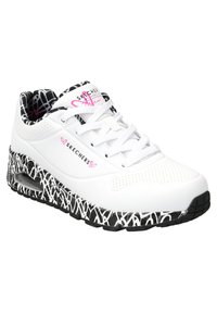 Baskets blanches avec une tige perforée, une semelle à motifs noir et blanc, et des accents roses. Comprend un système de laçage et un amorti d'air visible.