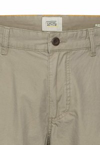 Lichtbeige katoenen shorts met een bruine knoop, gestikte details en een logo-label. Voorzien van een ritssluiting en zijzakken.