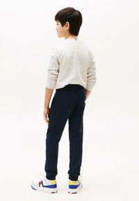 Grå sweatshirt med oprullede ærmer, marineblå sweatpants og multikolor sneakers med blå, gule og røde accenter.