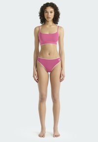 Roze katoenen sportbeha en bijpassende hoog uitgesneden bikini, voorzien van witte biezen en een klein logo op elk stuk. Soepele textuur, minimalistisch ontwerp.