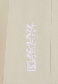 Bežna tkanina s glatkom teksturom, s bijelim izvezenim logotipom "KAIL SPORT" i geometrijskim amblemom, uredno postavljenim sa strane.