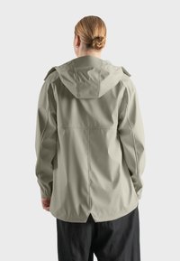 Chaqueta impermeable gris claro con capucha, que cuenta con un corte relajado, puños elásticos y una espalda ventilada para mayor transpirabilidad.