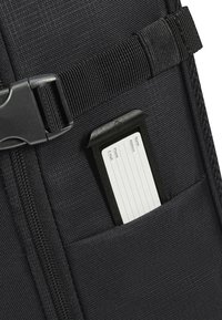 Black fabric pouch featuring a white rectangular card holder with lines for details. Adjustable strap and plastic buckle visible.