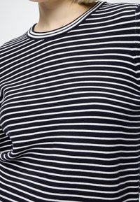 Pull tricoté à rayures bleu marine et blanches avec un col ras du cou côtelé. Texture douce, forme ajustée et motif à rayures horizontales régulières.