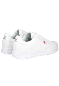 Zapatillas blancas con superiores de cuero suave, marcaje rojo en contraste, detalles perforados y acentos grises en el talón. Suela de goma plana.