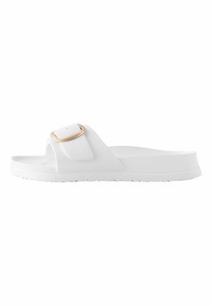 White slip-on sandal with a single wide strap and a gold-tone buckle, featuring a flat sole and textured footbed.