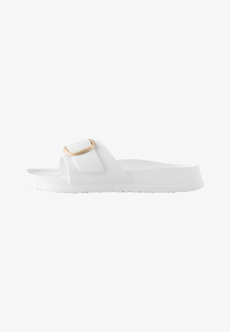 Sandalia blanca tipo slip-on con una única tira ancha y una hebilla de tono dorado, con suela plana y plantilla texturizada.