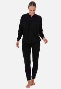 Chemise noire à boutons avec col, associée à un legging noir. Les deux vêtements ont une texture douce et une coupe ajustée.