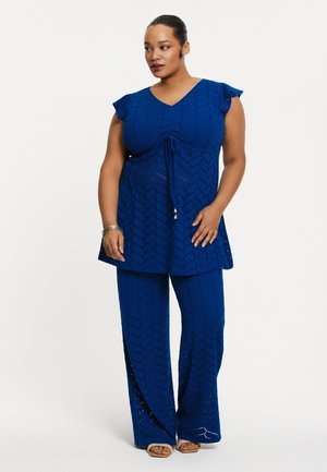 Blauwe tweedelige outfit bestaande uit een top met korte mouwen en een geknoopt voorpand, en een broek met wijd uitgesneden benen, beide met een textuurpatroon en een relaxte pasvorm.