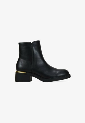 Bottines en cuir noir avec un bout arrondi, fermeture éclair latérale et un talon épais avec une bande dorée. Texture lisse.