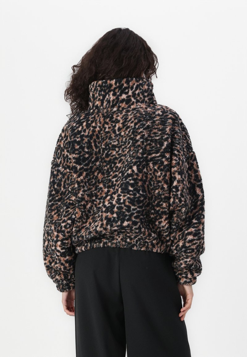 Pullover in velluto a coste con stampa leopardata, colletto alto, maniche a palloncino e orlo elastico. I colori includono nero, marrone e crema. Tessuto morbido.