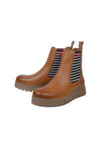 Bottines en cuir tan avec des côtés élastiques rayés noir et blanc, ornées d'accents en forme de cœur rouge et de semelles en caoutchouc texturé.