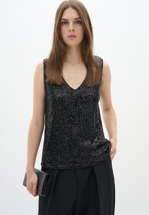 Top nero senza maniche con scollatura a V, ricoperto di paillettes, con una vestibilità comoda e una superficie liscia. Abbinato a pantaloni neri e una pochette.