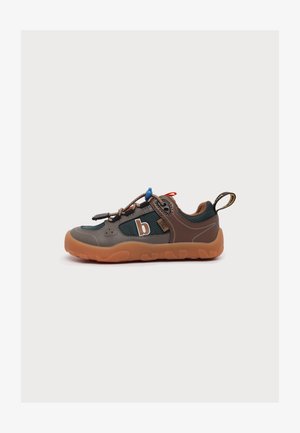 Basket basse avec des touches marron, noir et orange, semelle épaisse orange, lacets élastiques et languette au talon, sur fond neutre.