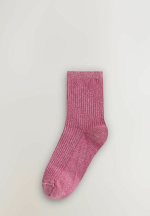 Üks roosa sooniku mustriga sokk koos volditud äärega, laotatud heleda halli pinna peale.