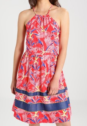 Sleeveless red dress with halter neck, tropical leaf and bird print, and two horizontal navy blue stripes near the hem.