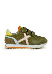 Zapatilla verde con malla gris y ante olivo, detalles en naranja, correas de velcro y una suela con patrón. Presenta un diseño de cruz blanca en el lateral.
