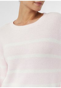 Jasnoróżowy sweter z prążkowanym okrągłym dekoltem, z białymi poziomymi paskami, dzianinową teksturą i lekko luźnym krojem.