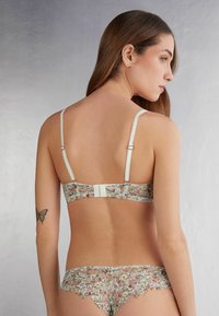 Bloemachtige kant bralette met verstelbare bandjes, haak-en-oogsluiting op de rug en bijpassende kanten slipjes. Zachte pastelkleuren en delicate textuur.