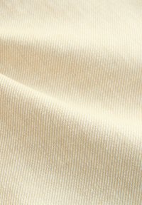 Baumwollstoff in einer hellbeigen Farbe mit feiner Rippenstruktur, die subtile Variationen in der Schattierung und eine glatte Oberfläche aufweist.