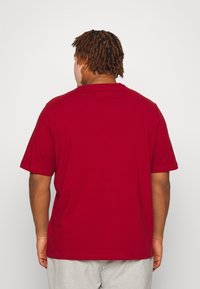 Burgundy short-sleeve t-shirt with a round neck; made of soft cotton. Smooth texture, simple design, and straight cut. No visible logos.