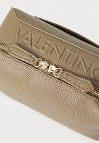 Beige texturovaná kožená taška se zlatým kováním, s embosovaným nápisem "VALENTINO" na vrchu a zipovým uzávěrem s dekorativními táhly na zip.