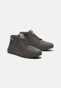 Zapatos de cuero gris oscuro de caña alta con un acabado suave, punta redondeada y cordones tonales. Presentan un acento de cuero marrón claro en la lengüeta.