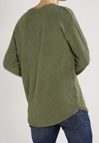 Maglione verde lavorato a maglia con un motivo testurizzato, scollo rotondo e vestibilità comoda. Presenta spacchi laterali e una linea dell'orlo posteriore più lunga.
