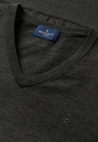 Donkergrijze v-hals trui van zachte stof, met een klein geborduurd logo op de borst en een merklabel in het blauw.