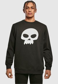 Felpa nera in un materiale morbido con una grande grafica di teschio bianco al centro. Il design presenta un collo rotondo e polsini a coste.