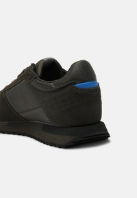 Scarpa da ginnastica nera con una parte superiore in suede e mesh testurizzati, con un accento blu sul tallone e una suola in gomma resistente.