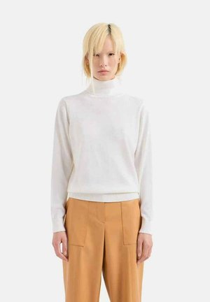 Maglione bianco a collo alto realizzato in un tessuto morbido, con maniche lunghe e orlo a costine, abbinato a pantaloni beige larghi.