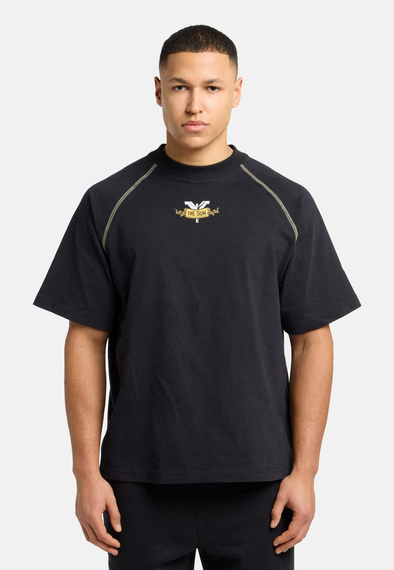 Zwarte katoenen t-shirt met korte mouwen, ribbelkraag en gouden logo-bekleding op de borst. Beschikt over contrasterende stiksels langs de schouders.