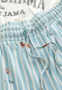 Světle modré a bílé pruhované pyžamové kalhoty s elastickým pasem, šňůrkou a malými potisky zvířat po celém materiálu.