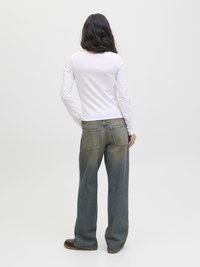 Hvit langermet topp med rund hals, kombinert med løstsittende, falmede blå denimjeans som har to baklommer og en lett frynset kant.