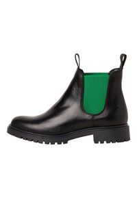 Botte Chelsea en cuir noir avec un panneau latéral élastique vert, équipée de languettes de tirage et d'une semelle noire robuste. Texture lisse et design à bout arrondi.