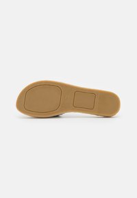 Tan rubber sole with a textured surface and ridged accents, featuring molded sections and size indicator "37" on the bottom.