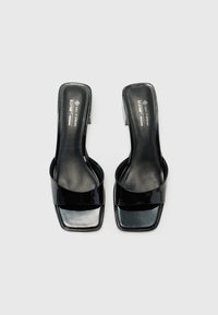 Black vegan leather slide-on shoes with a square toe and modest heel, featuring a glossy finish and a wide strap across the vamp.