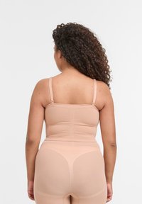 Be�żowy, bezszwowy top na ramiączkach i legginsy wykonane z miękkiego materiału, z regulowanymi ramiączkami i marszczonym wzorem z tyłu.