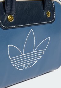 Blue leather bag with white stitched Adidas trefoil logo, black leather handle attachment, and gold button accents.