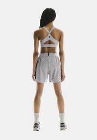Grauer Sport-BH mit ausgeschnittenem Rücken, kombiniert mit hellgrauen Shorts. Merkmale sind eine bequeme Passform und feuchtigkeitsableitendes Material.