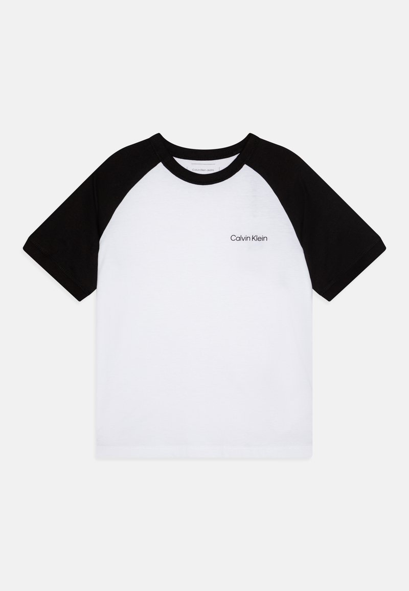 Musta raglan-lyhythihainen T-paita, jossa on valkoinen vartalo, mustat hihat ja pieni "Calvin Klein" -logo vasemmassa rinnassa.